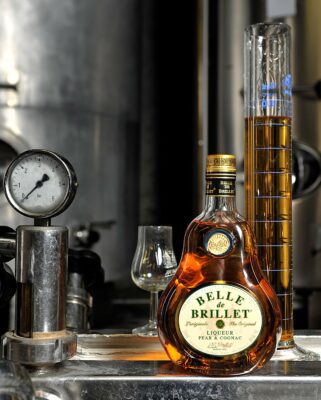 Une bouteille de la distillerie Belle de Brillet devant leur alambic